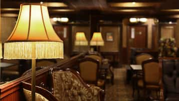 A hotel lobby with a large lamp, wooden furniture, and a carpeted floor.