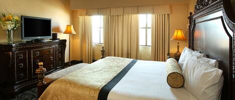 Une chambre d’hôtel avec un lit, une commode, une télévision et deux lampes.