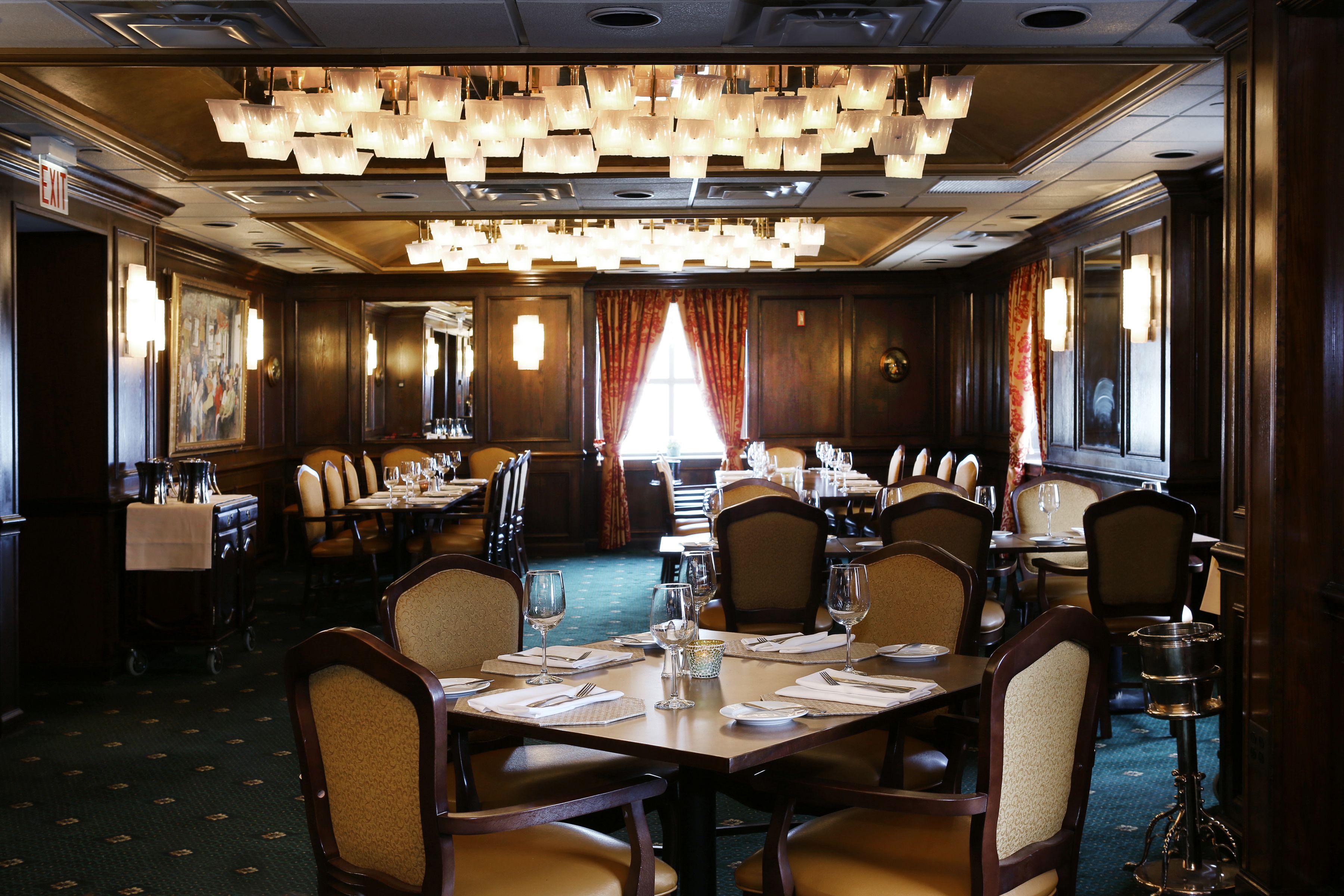 A formal dining room with multiple tables, chairs, and a chandelier.