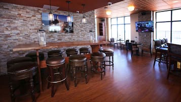 A bar area with wooden stools, a long bar counter, and a brick wall.