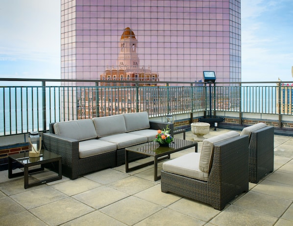 A rooftop terrace with a sofa, chairs, and a table.