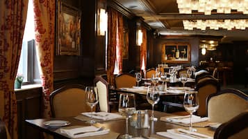Un restaurante con mesas dispuestas para comer, que cuenta con candelabros y cuadros en las paredes.