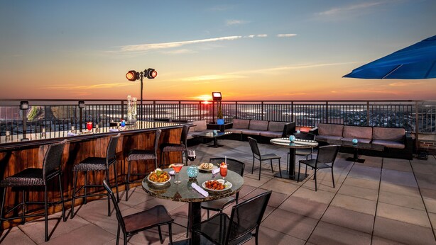 A rooftop bar with outdoor seating, a sunset view, and a cityscape in the background. - The Claridge Hotel (Atlantic City)