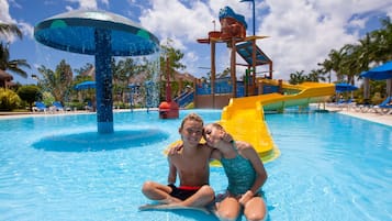 Un parc aquatique doté d’une grande fontaine, de toboggans et de chaises longues.