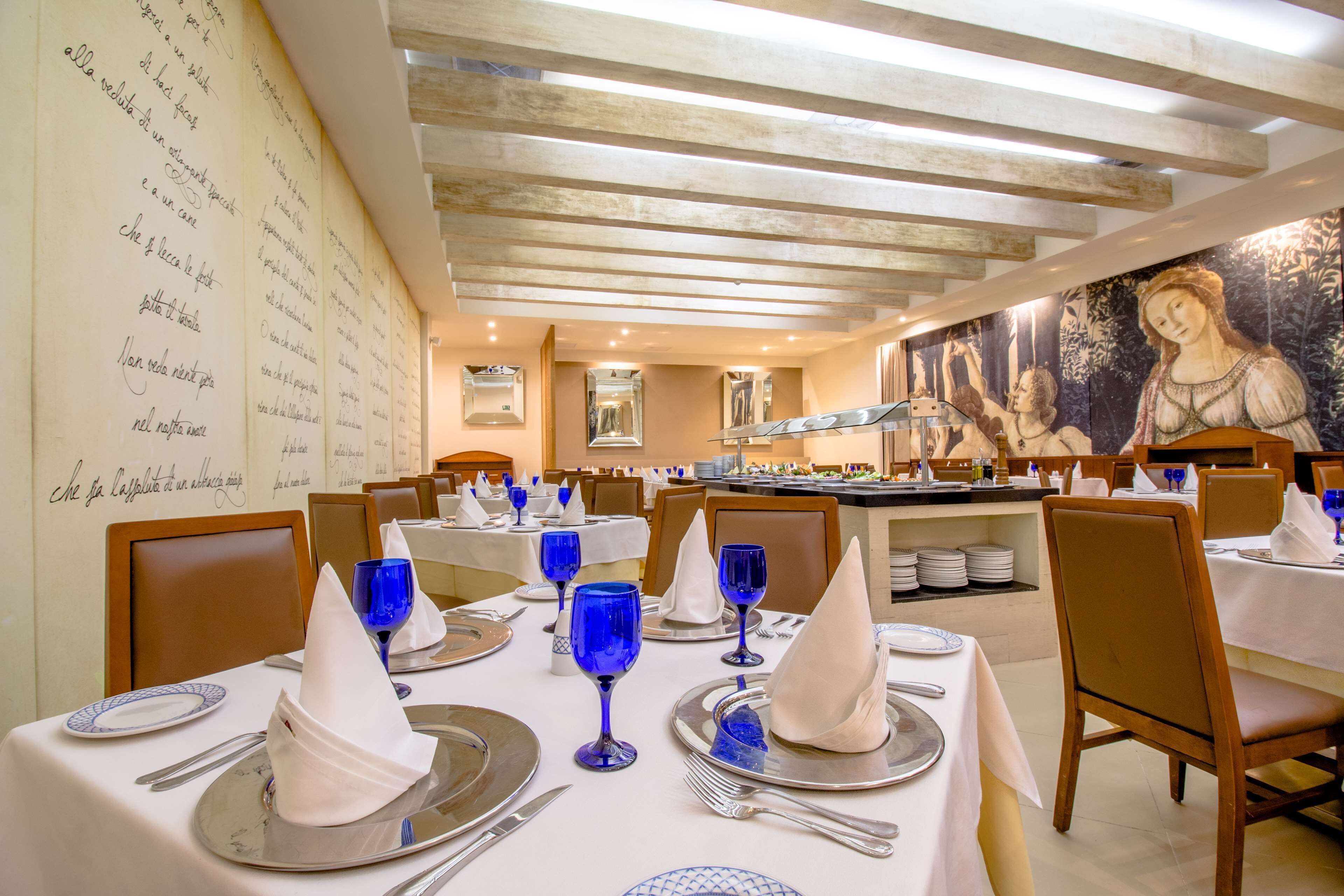 Un restaurant où les tables sont dressées pour le service, avec des verres à vin bleus et des serviettes blanches.