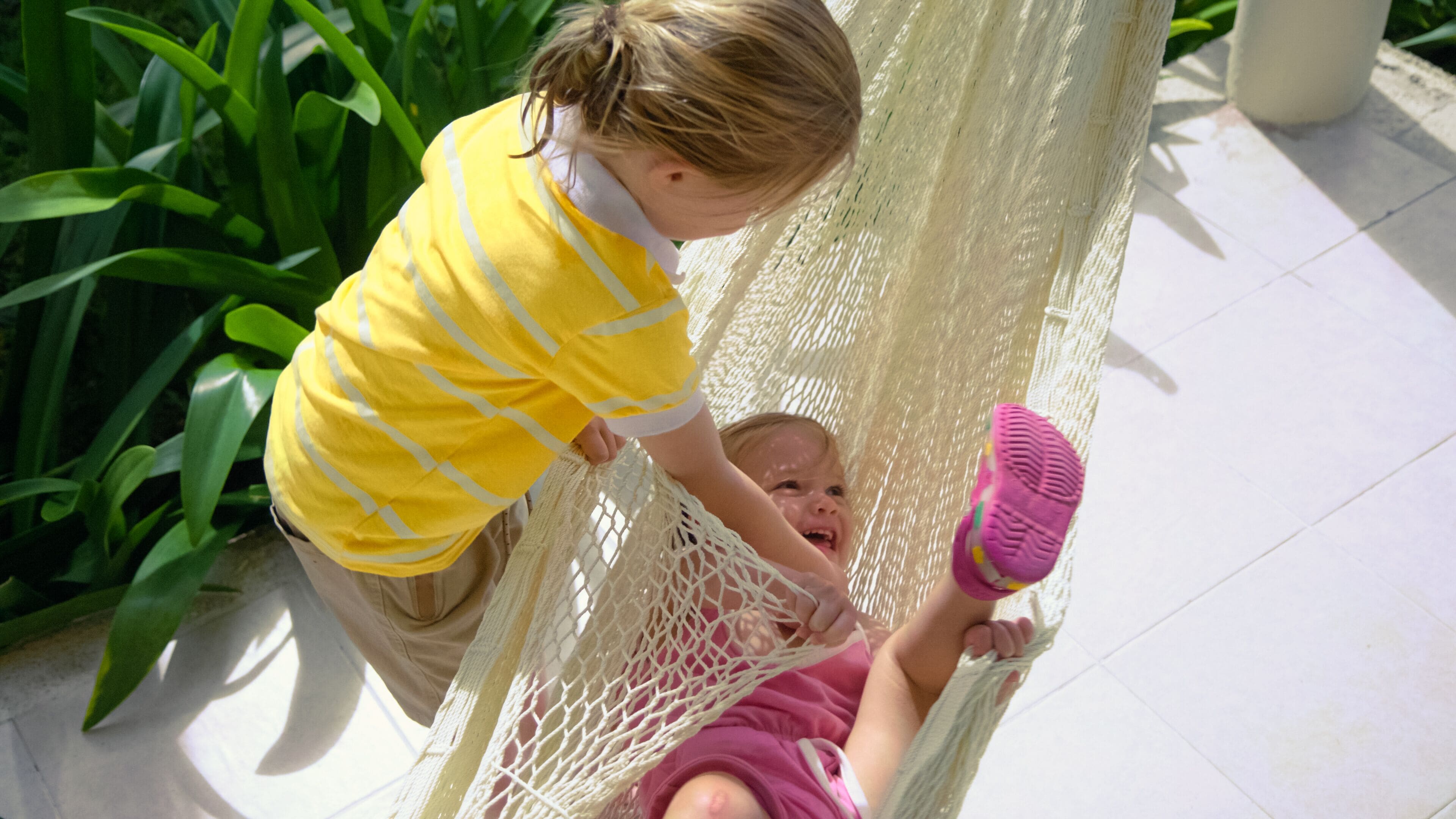 A child in a hammock with a pink shoe.