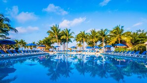 A pool with blue lounge chairs and umbrellas, surrounded by palm trees. - Allegro Cozumel All Inclusive (Cozumel)