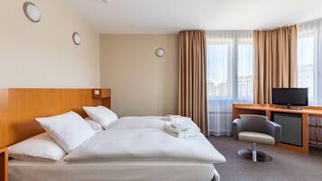 Ein Hotelzimmer mit einem Bett, einem Schreibtisch mit Fernseher und einem Sessel.