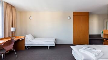 A hotel room with a bed, a desk, a chair, a wardrobe, and a bathroom.