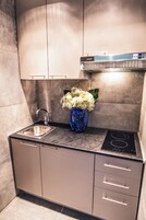 Una cocina moderna con estufa a gas empotrada, pileta de acero inoxidable y un florero con flores en la encimera.