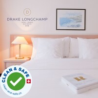Una habitación de hotel con una cama, una mesita de noche con lámpara y un cuadro enmarcado en la pared.