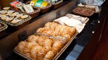 A breakfast buffet with various pastries, bread, and condiments.