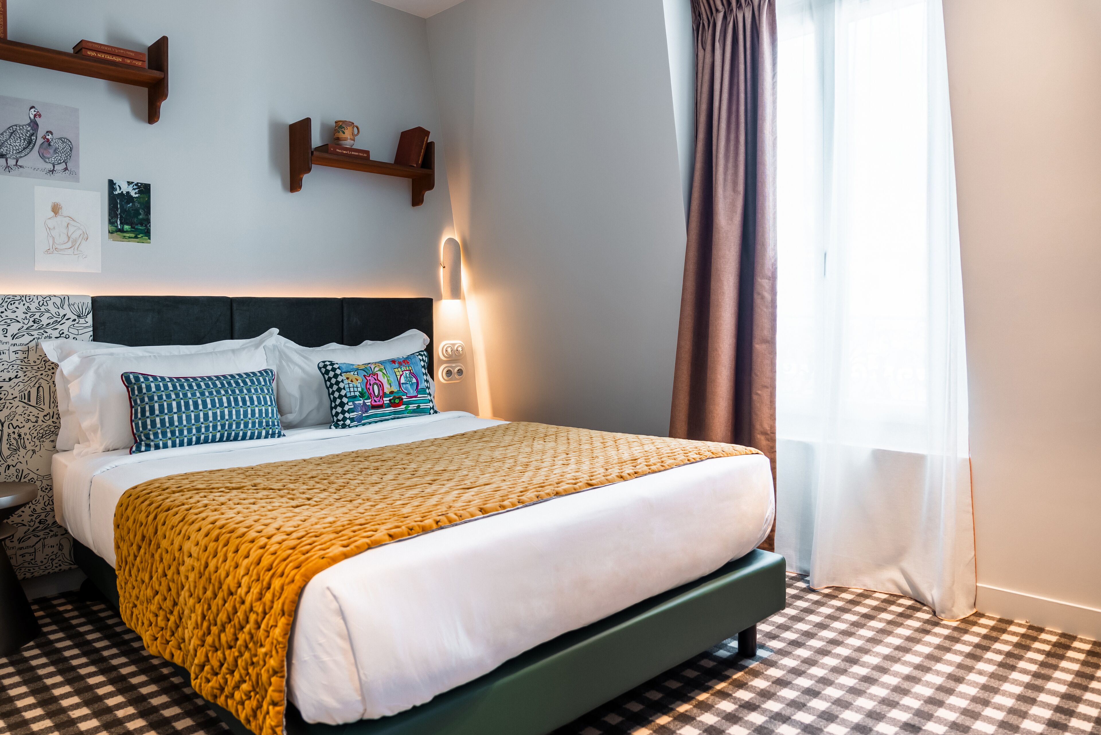 Uma cama bem arrumada com colcha estampada, cabeceira e mesa de cabeceira com abajur.