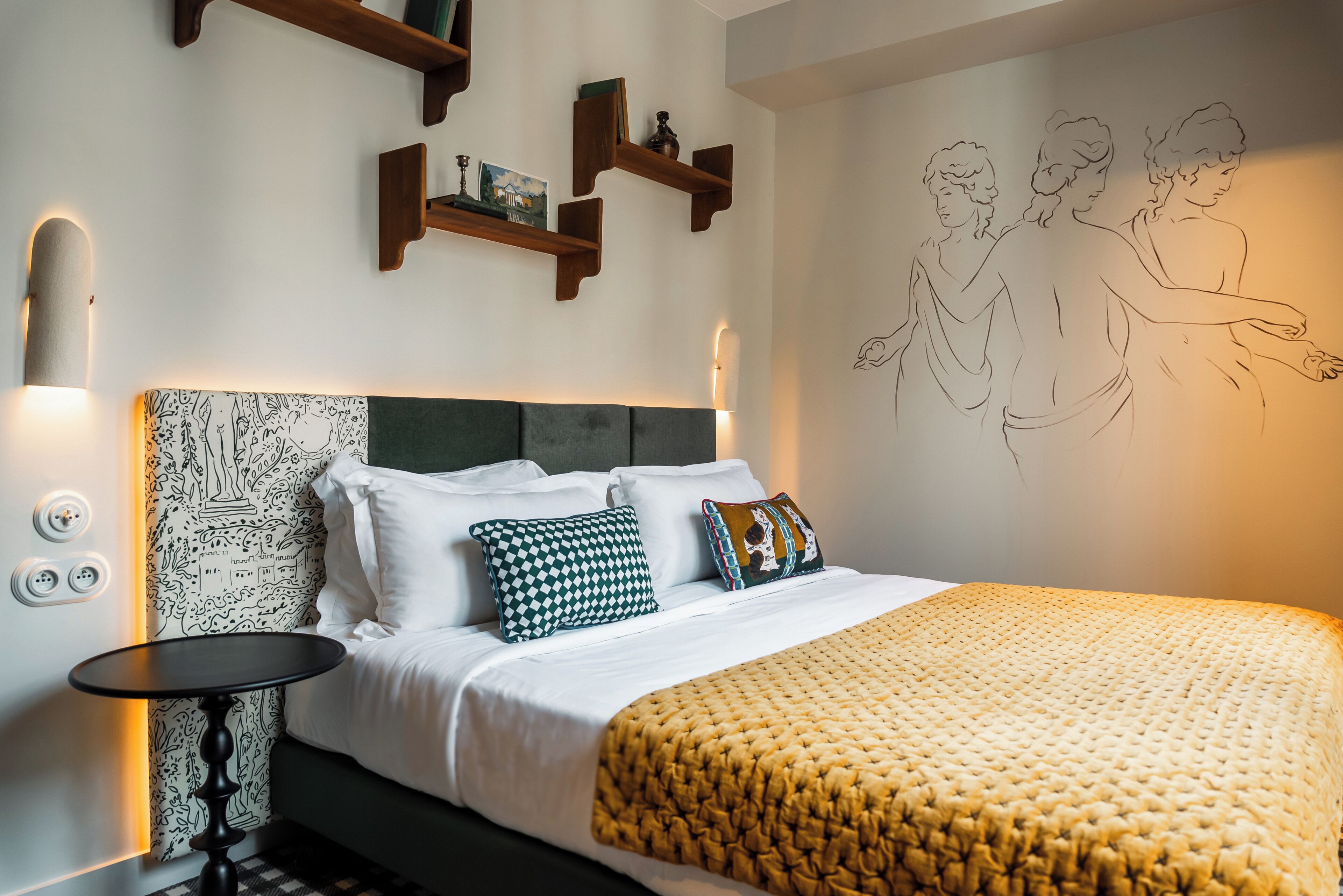 A neatly arranged bedroom with a bed, bedside table, and wall-mounted shelves.