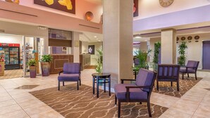 A hotel lobby with seating areas, a reception desk, and a Coca-Cola refrigerator. - Comfort Suites Maingate East (Kissimmee)