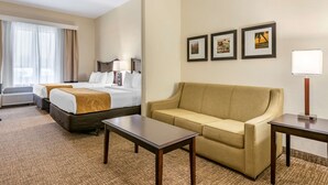 A hotel room with a bed, a sofa, a coffee table, and a desk. There are three framed pictures on the wall. - Comfort Suites Maingate East (Kissimmee)