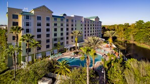 A multi-story hotel with a swimming pool surrounded by palm trees and greenery. - Comfort Suites Maingate East (Kissimmee)