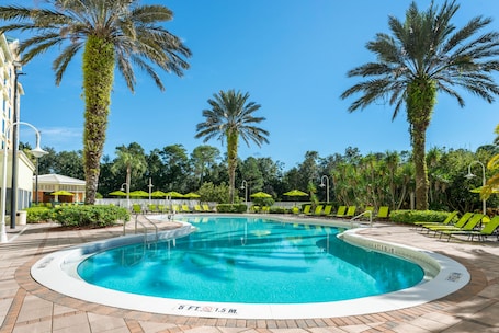 Una piscina al aire libre, sombrillas, sillones reclinables de piscina