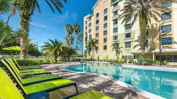 Una piscina al aire libre, sombrillas, sillones reclinables de piscina
