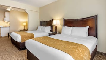 A hotel room with two beds, a desk, and a mirror.