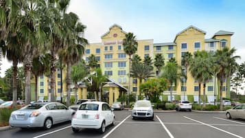 Un hotel amb façana groga, diversos balcons i palmeres.