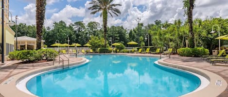 Una piscina con un límite de profundidad de 1,5 metros, rodeada de palmeras y sillas de descanso.