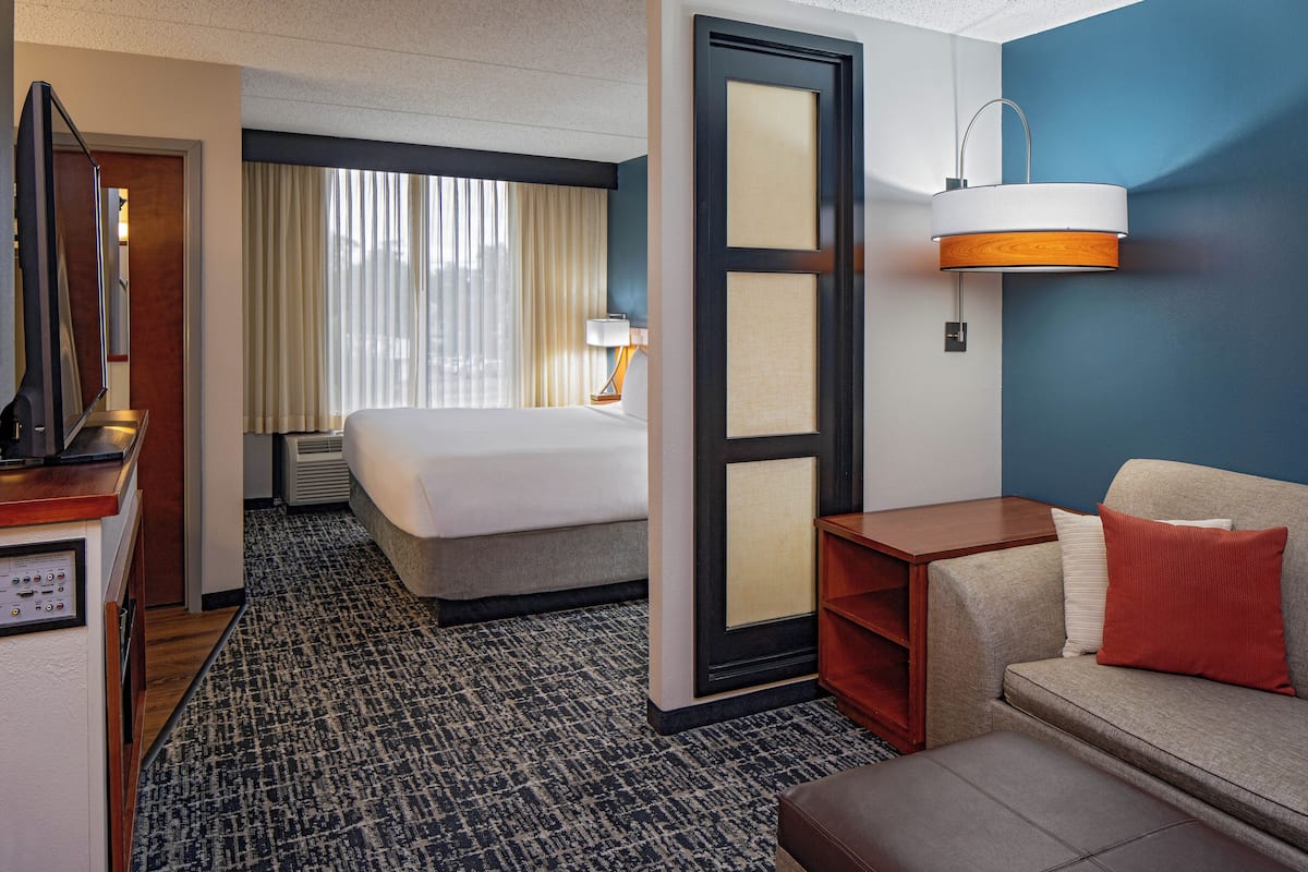 Ein Hotelzimmer mit Bett, Sofa, Schreibtisch und Bad.
