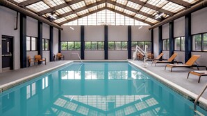 An indoor swimming pool with clear blue water, surrounded by lounge chairs and a high ceiling with skylights. - Hyatt Place Fair Lawn Paramus (Fair Lawn)