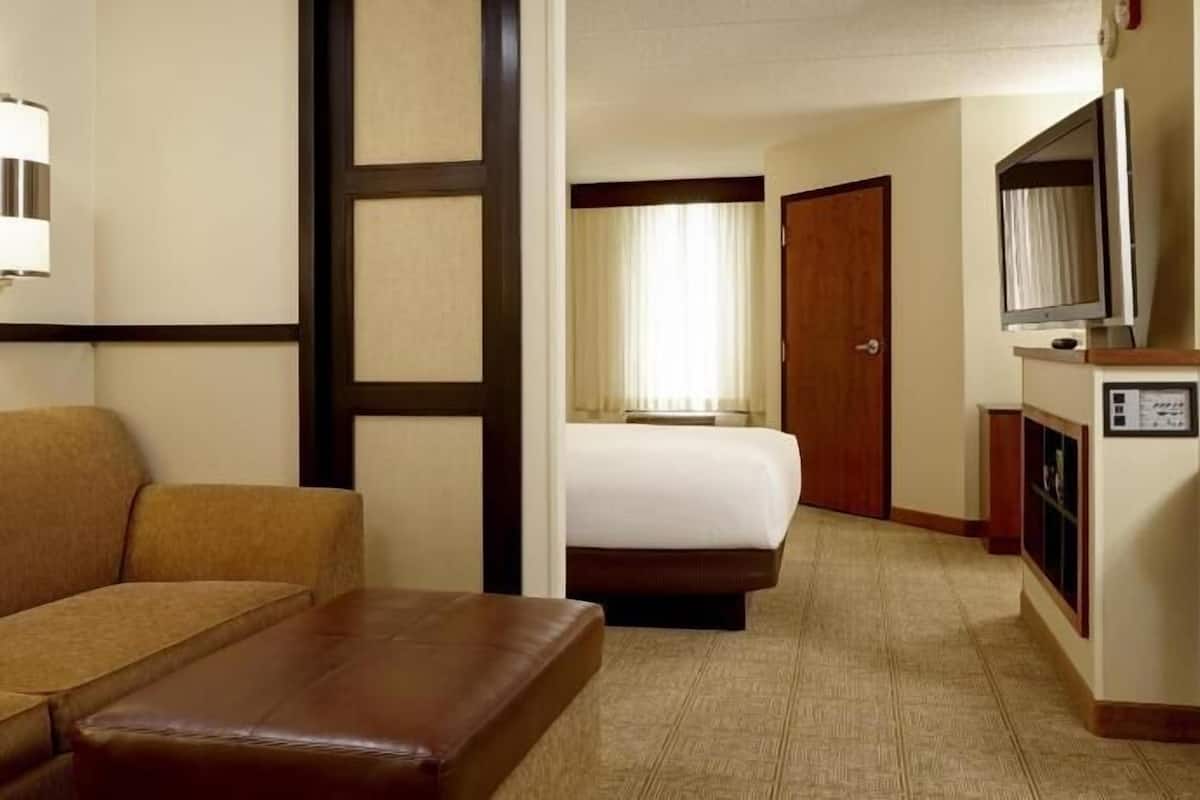 Ein Hotelzimmer mit Sofa, Bett, Schreibtisch und Telefon sowie einem Fernseher.