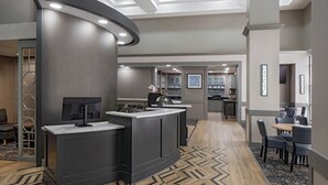 A modern hotel lobby with a reception desk, seating area, and a kitchen in the background. - Hyatt Place Fair Lawn Paramus (Fair Lawn)