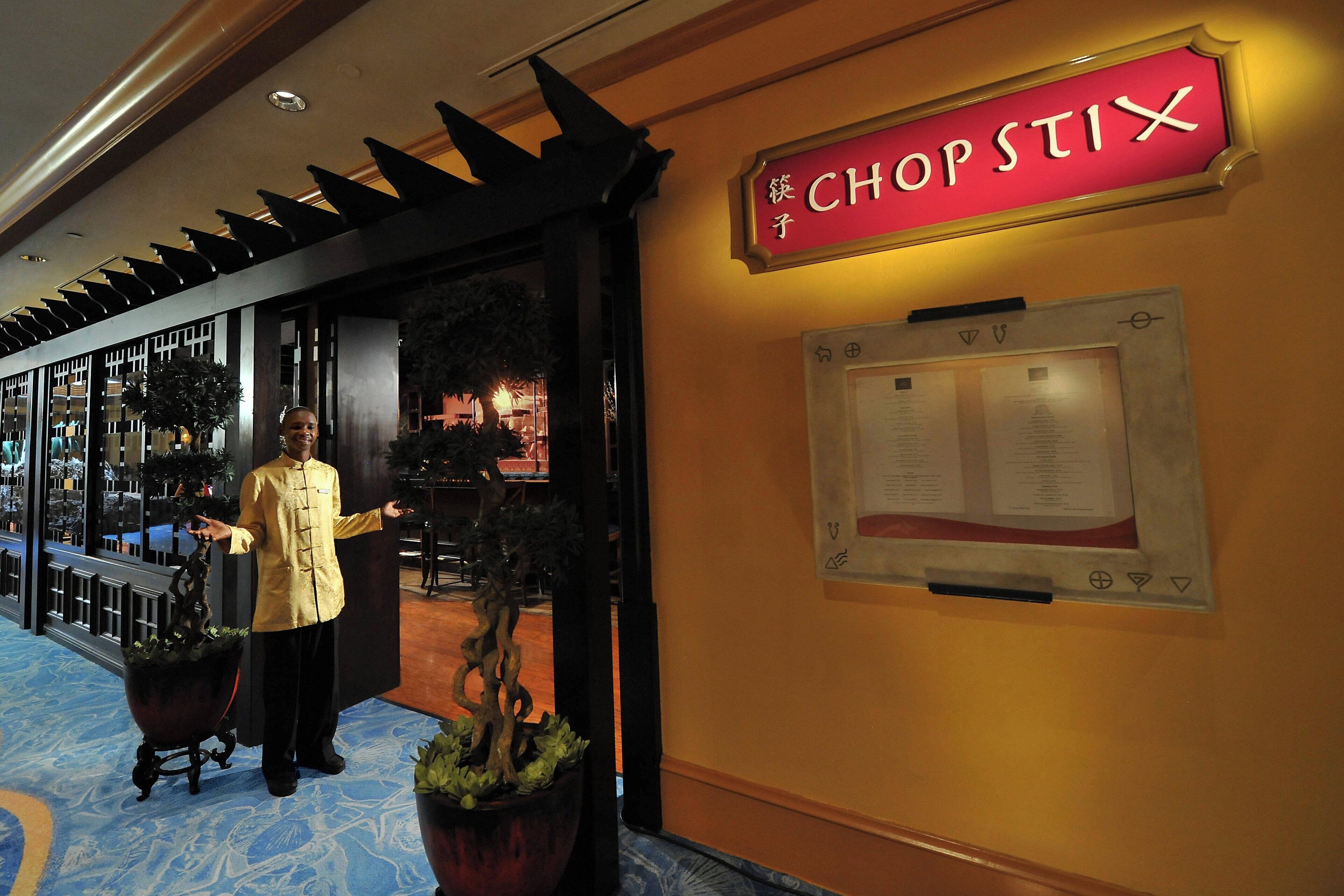 A hotel entrance with a sign reading "CHOPSTIX" and a menu board on the wall.