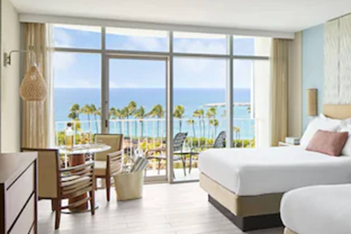 Ein Hotelzimmer mit großzügigem Balkon, einem Bett, einem Schreibtisch und einem Stuhl.