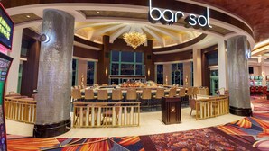 A bar area with a central bar, multiple seating arrangements, and a chandelier.