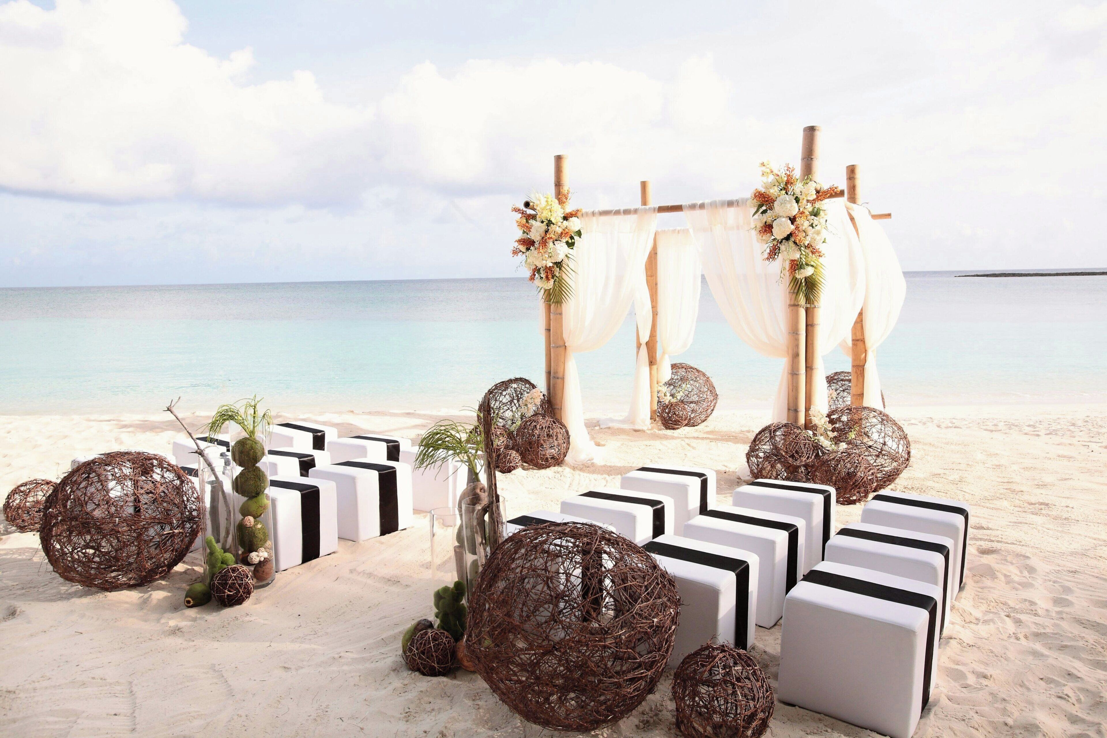 Decoración para una boda en la playa, con un arco blanco y flores.