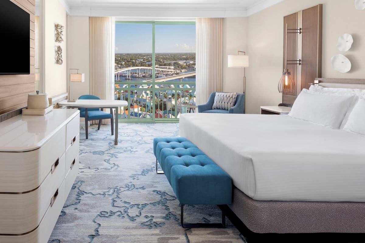 A hotel room with a large bed, a seating area with a view, a desk, and a TV.