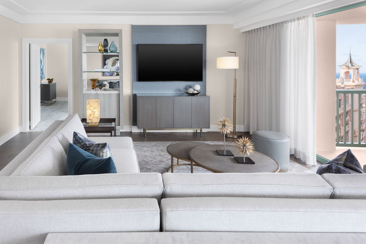 A modern living room with a grey sofa, a flat-screen TV, a coffee table, and a bookshelf.