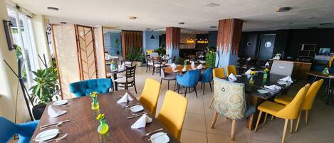 Un restaurante con varias mesas, sillas y una zona de bar.