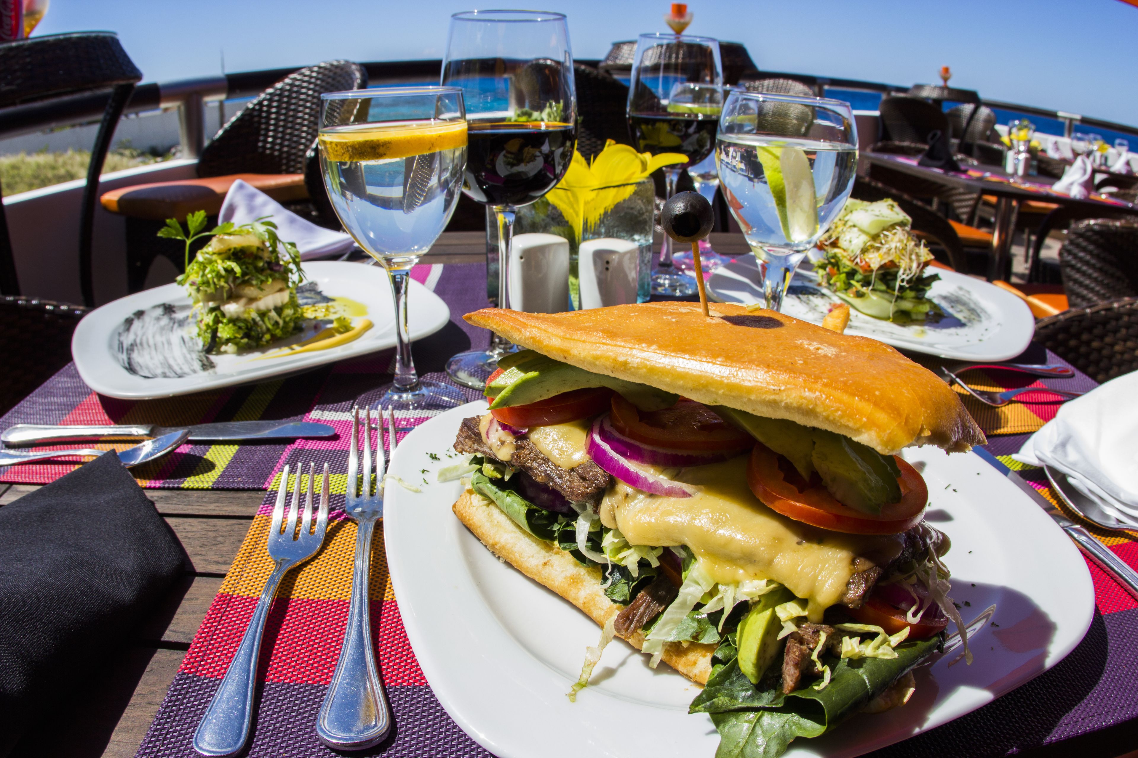 Eine Mahlzeit mit Sandwich und Salat an einem Tisch mit Blick auf das Meer.
