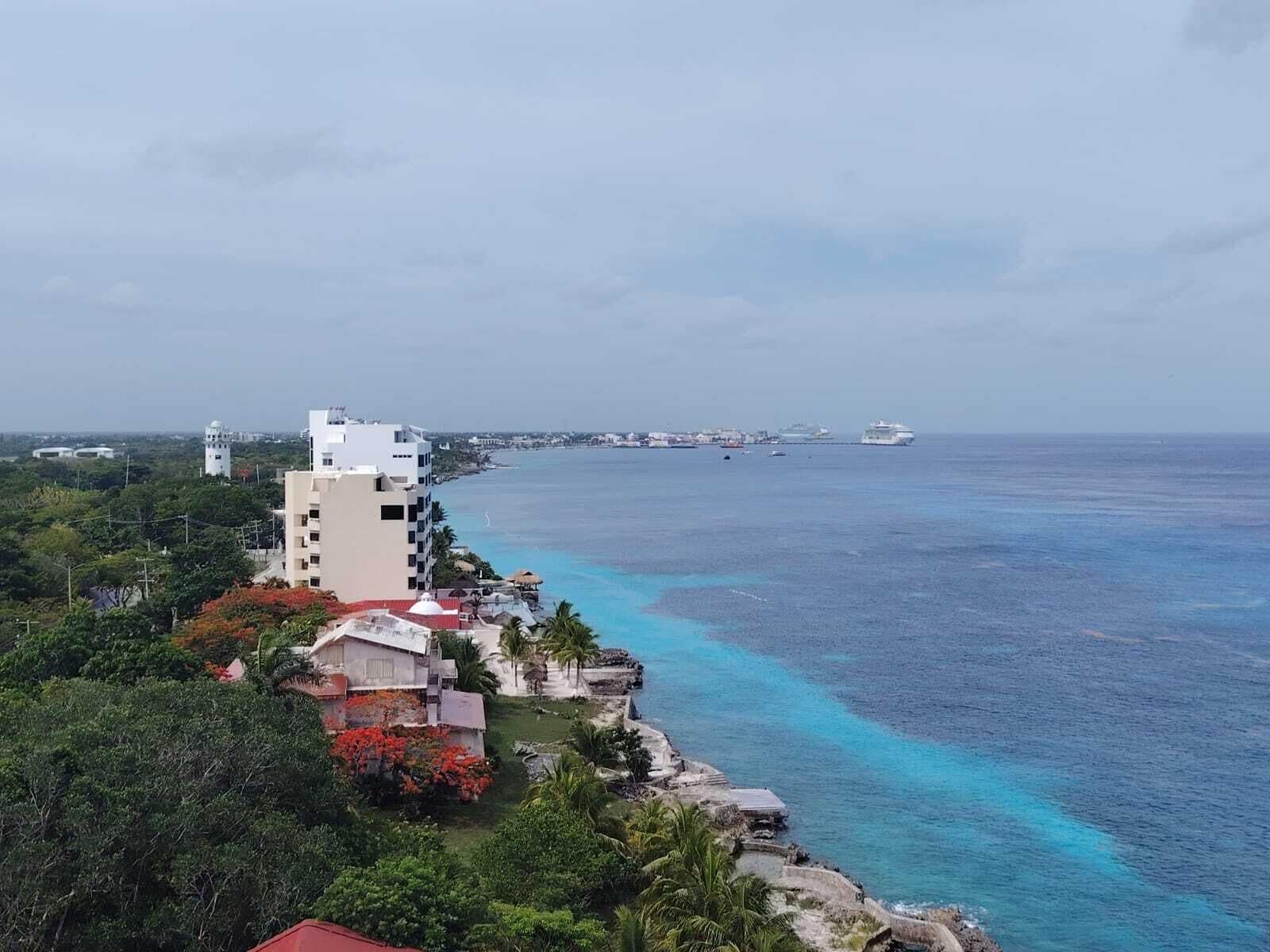 A coastal hotel with a view of the ocean and a distant cityscape.