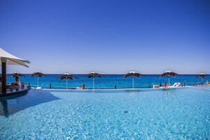 Una piscina al aire libre, sombrillas, sillones reclinables de piscina