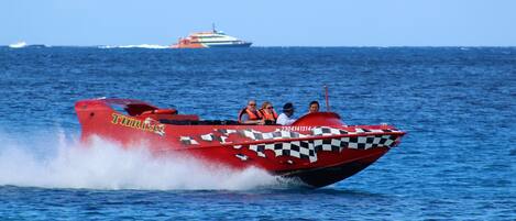 A red speedboat with the name "THRILLER" and a checkered pattern on its side, moving through the water.