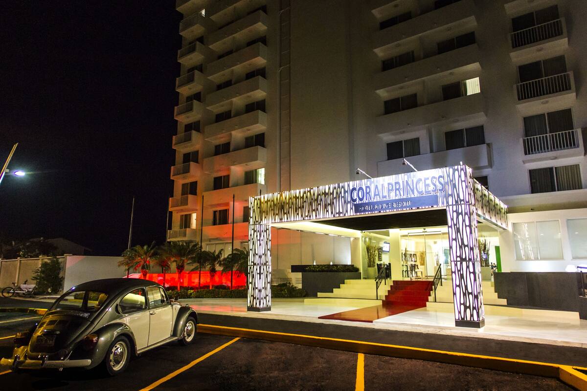 Een hotelingang met een bord waarop 'Princess Hotel' staat en een geparkeerde auto ervoor.