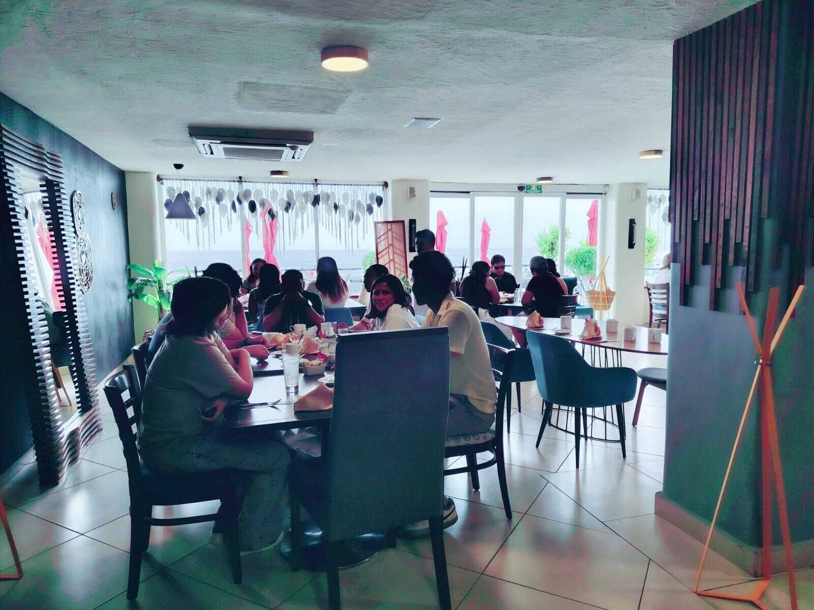 Ein Restaurant mit Tischen, Stühlen, einem Deckenventilator und Blick durch die Fenster.