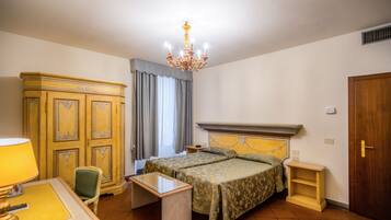 Ein Schlafzimmer mit einem Bett, einem Schreibtisch, einem Stuhl, einem Kleiderschrank und einer Chandelüster.