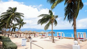 A beach with palm trees, beach chairs, and a sign. - Grand Decameron Montego Beach, A Trademark All Inc (Montego Bay)