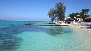 A beach with clear turquoise water, a pier, and beach chairs. - Grand Decameron Montego Beach, A Trademark All Inc (Montego Bay)