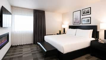 Habitación de hotel con cama, mesitas de noche, televisor, chimenea y cuadros en la pared.