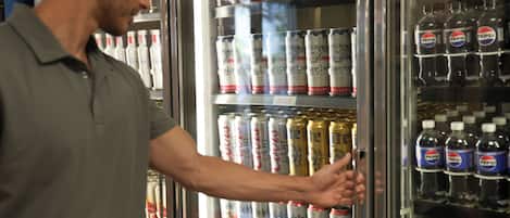 A person selecting beverages from a refrigerated display case containing various drinks.