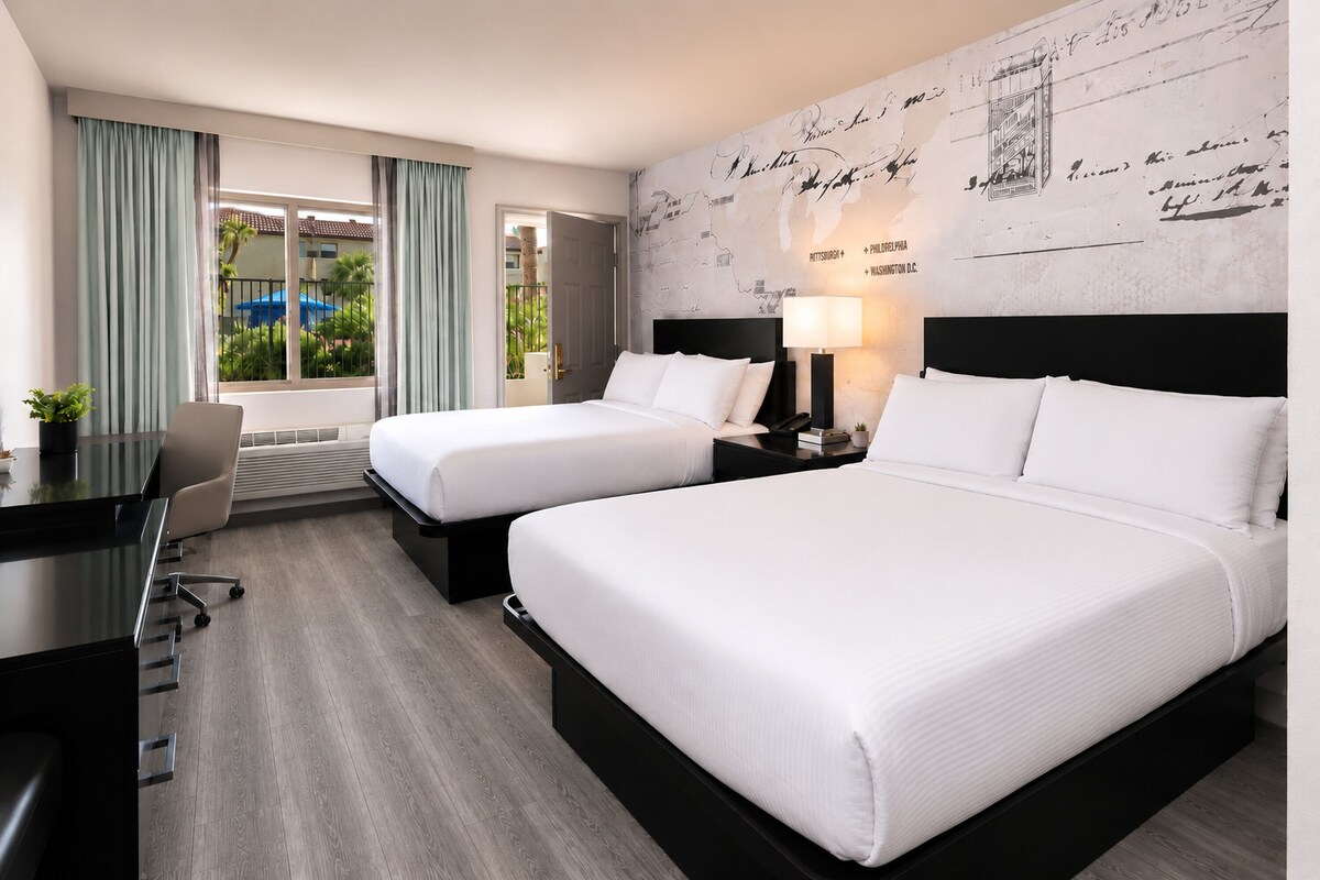Een hotelkamer met twee bedden, een bureau en uitzicht op het landschap.