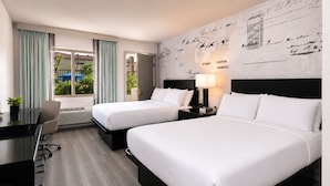 Habitación de hotel con dos camas, un escritorio y vistas al exterior.